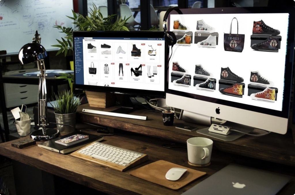 Picture of POD fashion items on 2 computer screens on a desk.